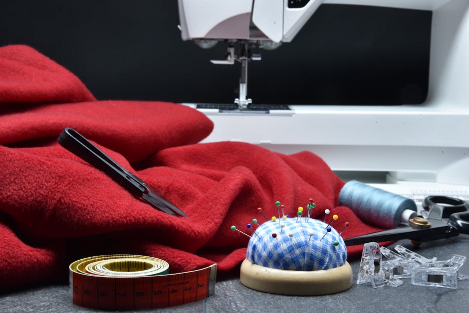 A sewing setup featuring red fabric, sewing machine, and tools. Ideal for crafting concepts.